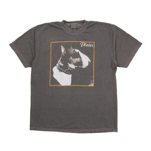 May include: A charcoal gray short-sleeve t-shirt featuring a square graphic print on the chest. The print displays a profile view of a bull terrier wearing a studded collar, with the word Pixies written in white script in the top right corner.