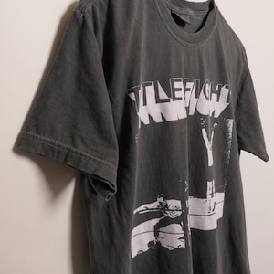 May include: A black t-shirt with a white graphic print of the word "Title Fight" and a silhouette of a person.