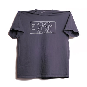 May include: A dark gray short-sleeve t-shirt featuring a white rectangular graphic on the chest. The graphic contains a line drawing of two figures running and the text "death cab for cutie" printed in a simple, lowercase sans-serif font.