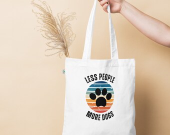 May include: White canvas tote bag with a retro-style graphic of a paw print in a circle with the text "Less People More Dogs".