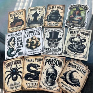K&ouml;nnte beinhalten: Eine Sammlung von elf rechteckigen Aufklebern mit Etiketten im Vintage-Apothekenstil, die Illustrationen von schwarzer Katze, Banshee, Kr&ouml;te, Hexe, Meerjungfrau, Aug&auml;pfeln, Totenkopf, Schlange, Spinne und Mond in schwarzer Tinte auf cremefarbenem Papier zeigen.