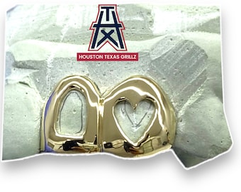 May include: Gold grillz with a heart and a circle design. The grillz are set in a mold. The text "HOUSTON TEXAS GRILLZ" is visible in the image.