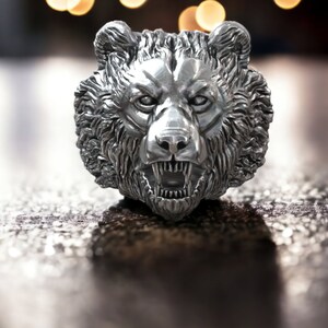 Roaring bear head ring, wild animal inspired statement jewelry, symbolic warrior band, and handcrafted bold accessory designed for those who are drawn to strength, dominance, and fearless energy. This striking ring features a detailed roaring bear head motif with open jaws, sharp teeth, and intense engraved textures, creating a powerful and aggressive appearance inspired by nature, Viking symbolism, and primal force.