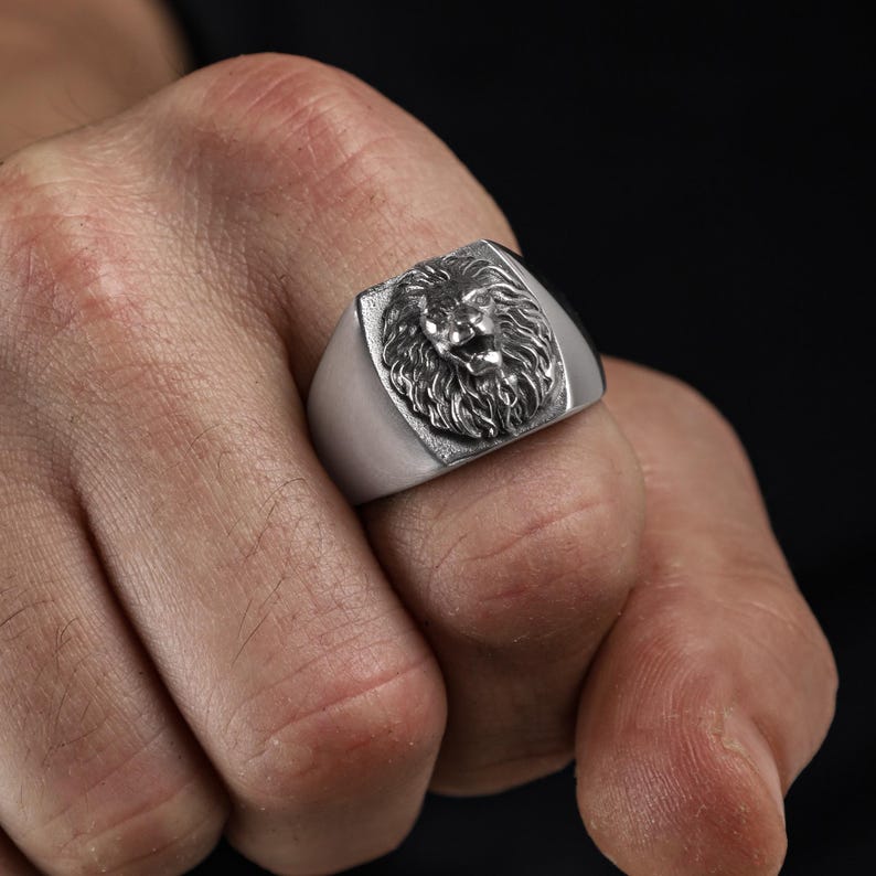 African lion ring, safari inspired lion jewelry, symbolic king of the jungle statement band, and handcrafted bold accessory designed for those who are drawn to strength, courage, and untamed masculine energy. This striking ring features a detailed African lion head motif with textured mane engravings and powerful facial details, creating a commanding appearance inspired by wildlife symbolism, tribal aesthetics, and fearless leadership.