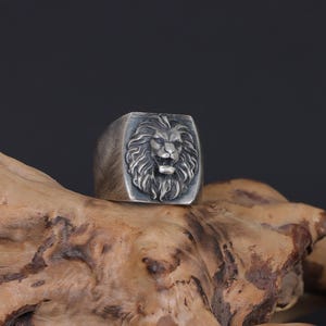African lion ring, safari inspired lion jewelry, symbolic king of the jungle statement band, and handcrafted bold accessory designed for those who are drawn to strength, courage, and untamed masculine energy. This striking ring features a detailed African lion head motif with textured mane engravings and powerful facial details, creating a commanding appearance inspired by wildlife symbolism, tribal aesthetics, and fearless leadership.