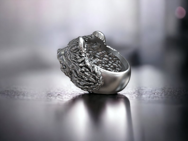 Roaring bear head ring, wild animal inspired statement jewelry, symbolic warrior band, and handcrafted bold accessory designed for those who are drawn to strength, dominance, and fearless energy. This striking ring features a detailed roaring bear head motif with open jaws, sharp teeth, and intense engraved textures, creating a powerful and aggressive appearance inspired by nature, Viking symbolism, and primal force.