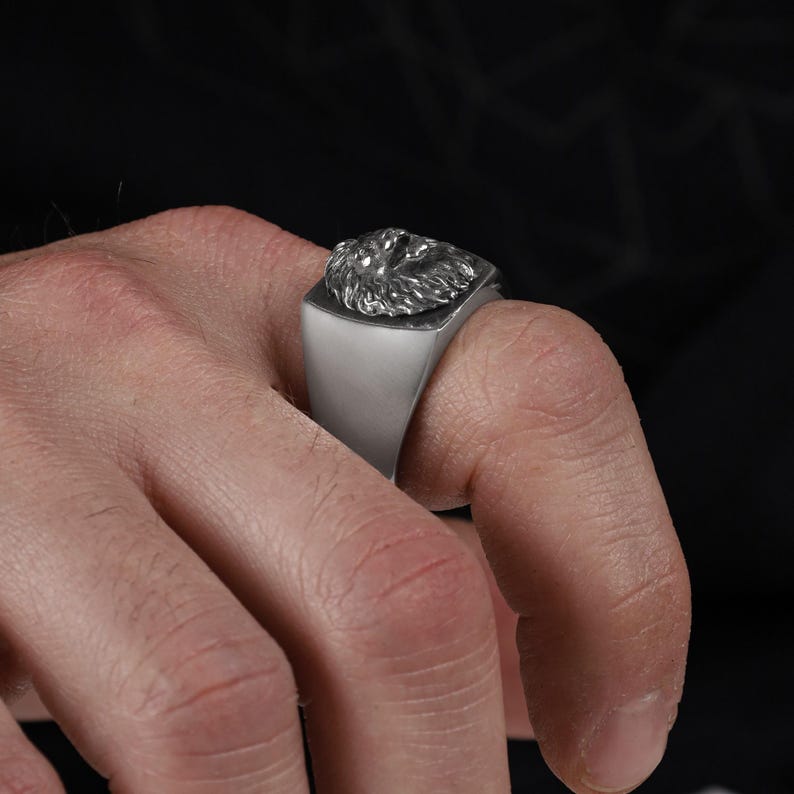 African lion ring, safari inspired lion jewelry, symbolic king of the jungle statement band, and handcrafted bold accessory designed for those who are drawn to strength, courage, and untamed masculine energy. This striking ring features a detailed African lion head motif with textured mane engravings and powerful facial details, creating a commanding appearance inspired by wildlife symbolism, tribal aesthetics, and fearless leadership.