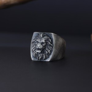 African lion ring, safari inspired lion jewelry, symbolic king of the jungle statement band, and handcrafted bold accessory designed for those who are drawn to strength, courage, and untamed masculine energy. This striking ring features a detailed African lion head motif with textured mane engravings and powerful facial details, creating a commanding appearance inspired by wildlife symbolism, tribal aesthetics, and fearless leadership.