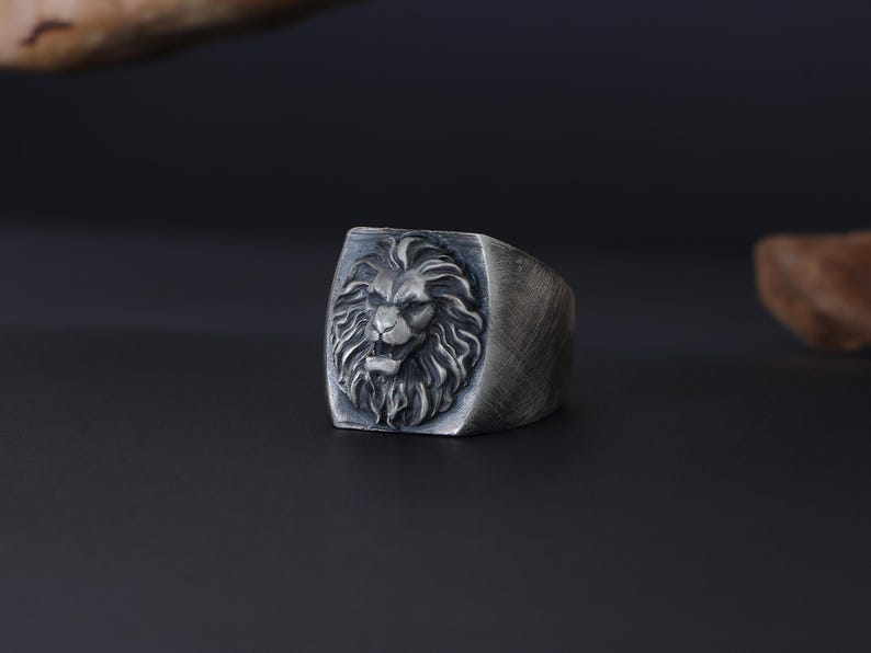 African lion ring, safari inspired lion jewelry, symbolic king of the jungle statement band, and handcrafted bold accessory designed for those who are drawn to strength, courage, and untamed masculine energy. This striking ring features a detailed African lion head motif with textured mane engravings and powerful facial details, creating a commanding appearance inspired by wildlife symbolism, tribal aesthetics, and fearless leadership.