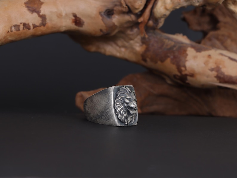 African lion ring, safari inspired lion jewelry, symbolic king of the jungle statement band, and handcrafted bold accessory designed for those who are drawn to strength, courage, and untamed masculine energy. This striking ring features a detailed African lion head motif with textured mane engravings and powerful facial details, creating a commanding appearance inspired by wildlife symbolism, tribal aesthetics, and fearless leadership.