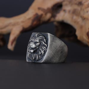 African lion ring, safari inspired lion jewelry, symbolic king of the jungle statement band, and handcrafted bold accessory designed for those who are drawn to strength, courage, and untamed masculine energy. This striking ring features a detailed African lion head motif with textured mane engravings and powerful facial details, creating a commanding appearance inspired by wildlife symbolism, tribal aesthetics, and fearless leadership.
