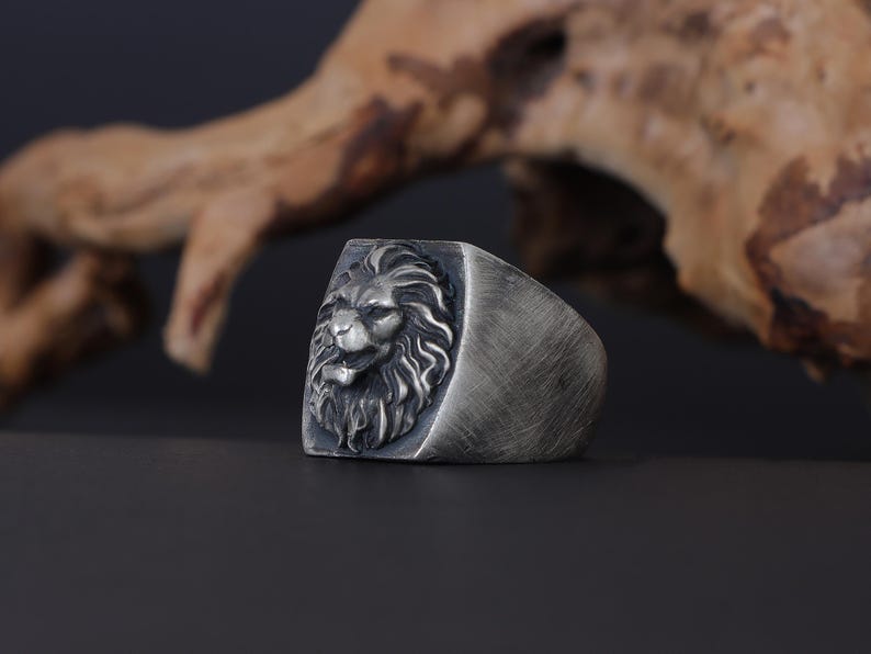 African lion ring, safari inspired lion jewelry, symbolic king of the jungle statement band, and handcrafted bold accessory designed for those who are drawn to strength, courage, and untamed masculine energy. This striking ring features a detailed African lion head motif with textured mane engravings and powerful facial details, creating a commanding appearance inspired by wildlife symbolism, tribal aesthetics, and fearless leadership.