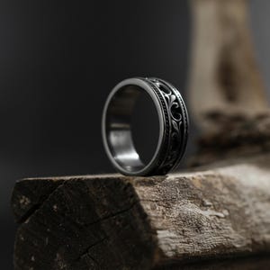 Puede incluir: Un anillo plateado con un intrincado dise&ntilde;o floral. El anillo es de metal y tiene un acabado pulido. El dise&ntilde;o presenta un patr&oacute;n repetitivo de hojas y vides arremolinadas. El anillo es de estilo banda, adecuado para el uso diario. Di&aacute;metro: aproximadamente 2 cm.