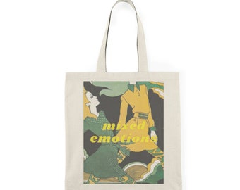 May include: A white tote bag featuring a vintage illustration of two people in green and yellow clothing. The text "mixed emotions" is printed in yellow on the bag.