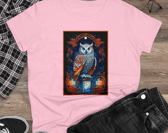 May include: A pink t-shirt with a graphic print of an owl perched on a candle. The owl has brown, orange, and blue feathers. The candle is dripping wax. The background is dark with a moon and stars.