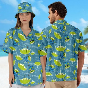 May include: Two blue and green patterned short-sleeved shirts with a repeating design of a green alien character. The shirts have a button-down front and a collar.