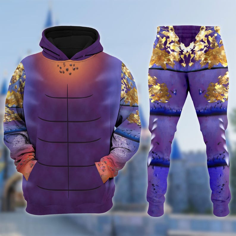 Puede incluir: Un conjunto de sudadera con capucha y pantal&oacute;n morado. La sudadera con capucha presenta una capucha negra, un dise&ntilde;o en el pecho y un bolsillo delantero. El conjunto tiene un dise&ntilde;o de l&aacute;mina dorada en los hombros, las mangas y el pantal&oacute;n.