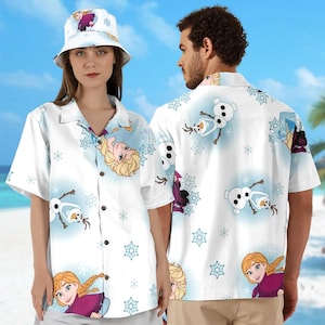 May include: Two white button-down shirts with a pattern of snowflakes, Olaf, and Anna from Frozen. The shirts have short sleeves and a collared neckline. One shirt is being worn by a person wearing a white bucket hat with a Frozen design.