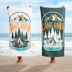 May include: Two beach towels, one white and one dark green, each featuring a camping-themed design. The design includes mountains, trees, a tent, and the text "CAMP ANNA" and "PARK CITY, UTAH". The date "SEPTEMBER 2025" is also displayed.