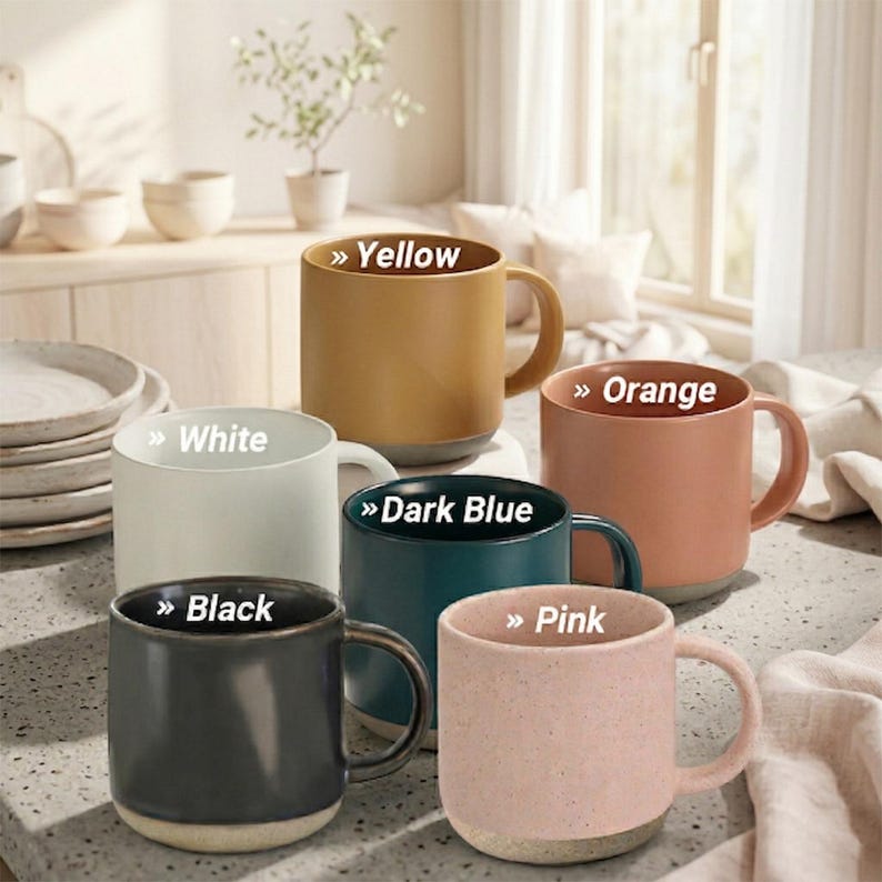Puede incluir: Una colecci&oacute;n de tazas de cer&aacute;mica en varios colores: amarillo, blanco, naranja, azul oscuro, negro y rosa. Cada taza tiene una forma redondeada, un asa y una base contrastante. Los colores est&aacute;n indicados en las tazas.