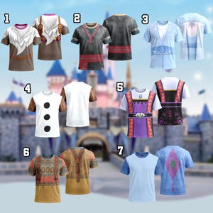 May include: Collection of seven short-sleeved t-shirts with various designs. The shirts feature different color schemes and patterns, including character-inspired graphics. The shirts are displayed against a blurred background of a castle, suggesting a theme park setting.