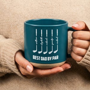 Puede incluir: Taza de cer&aacute;mica color turquesa con base beige, con ilustraciones de palos de golf blancos y nombres. El texto "BEST DAD BY PAR" est&aacute; impreso debajo. Un regalo perfecto para un entusiasta del golf.