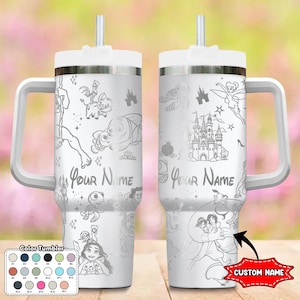 May include: A white tumbler with a handle and straw, featuring etched cartoon characters and the text "Your Name." The design includes a castle, fairy, and other characters. A color chart is shown at the bottom. The tumbler has a white lid and handle.