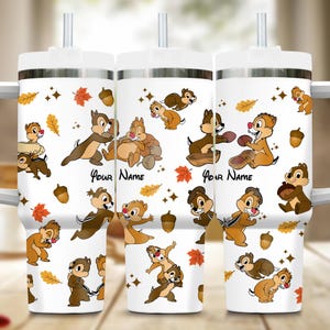 May include: Three white stainless steel tumblers with a fall-themed design featuring Chip and Dale characters, leaves, and acorns. The tumblers have a silver lid and a straw. The text "Your Name" is printed on each tumbler.