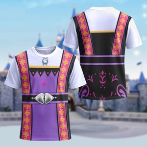 May include: White t-shirt featuring a design inspired by a princess costume. The front of the shirt has a purple bodice with a silver belt and a jewel. The design includes black and gold accents and floral patterns. The back of the shirt has a black panel with purple floral details.