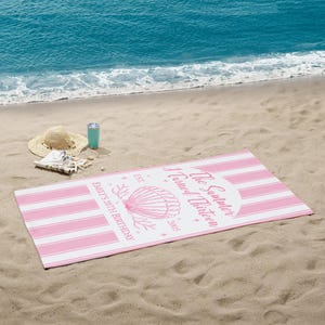 May include: A pink and white striped beach towel with the text "The Summer I Turned Thirteen" and "Emily's 20th Birthday" printed on it. A straw hat, a turquoise tumbler, and seashells are on the sand.