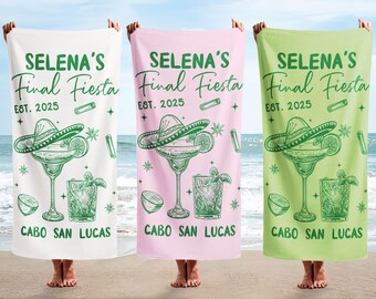 May include: Three beach towels in white, pink, and green, each featuring a margarita glass, sombrero, and the text "SELENA'S Final Fiesta EST. 2025 CABO SAN LUCAS" in green. The towels are held up on a sandy beach.