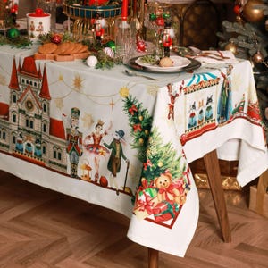 May include: White tablecloth with a Christmas Nutcracker theme. The tablecloth features a gingerbread house, a ballerina, a nutcracker, a rabbit, a Christmas tree, and a teddy bear with presents. The tablecloth is perfect for a holiday dinner party.