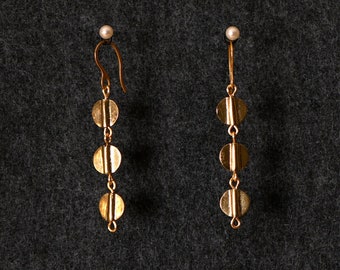 May include: A pair of gold earrings with three round, flat, gold discs hanging from each earring.
