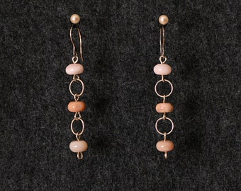 May include: A pair of silver earrings with three pink and brown beads on each earring.