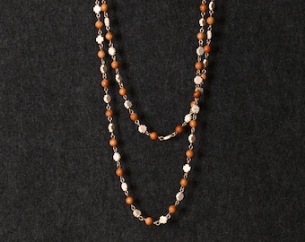 May include: A double strand necklace with brown wooden beads and white cross-shaped beads.