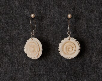 May include: A pair of white rose-shaped earrings with silver hooks.