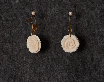 May include: A pair of white carved rose earrings with gold hooks.