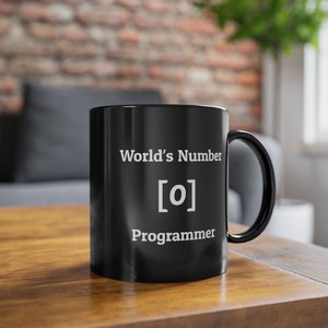 Op de afbeelding: Zwarte koffiemok met witte tekst die "World's Number [0] Programmer" luidt.