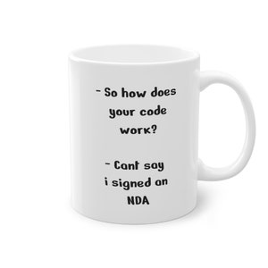 Op de afbeelding: Een witte keramische mok met zwarte tekst die luidt: "Dus hoe werkt je code? - Kan ik niet zeggen, ik heb een NDA getekend"
