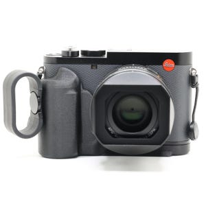 May include: A black camera with a lens and a red Leica logo. The camera has a black rubber grip and a black strap.