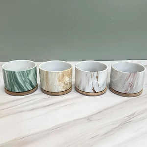 May include: A set of three ceramic mugs with a speckled, matte finish in cream, light grey, and dark grey. Each mug has a simple, minimalist design, suitable for coffee or tea.
