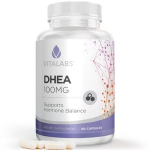 May include: A clear plastic bottle of Vitalabs DHEA 100MG dietary supplement. The label includes the Vitalabs logo, product name, dosage, and a statement about hormone balance support. The bottle contains 90 capsules, with a few capsules visible in front.