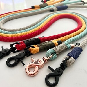 A collection of Paracord rope handle leads in various colours. Each lead has a common whipping knot at the clip end to secure the clip, and at  the handle, with an O-ring attached to the handle. Both ends of the rope are finished with metal cap ends