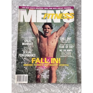 Peut inclure: Une couverture du magazine Men's Fitness d'octobre 1993. Elle présente un homme sortant de l'eau, les bras levés. Titres : "Great Workout" et "Sexual Performance". Le magazine promeut un mode de vie sain.