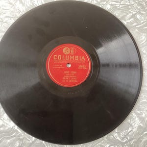 May include: A black vinyl record with a red Columbia Records label. The label has the text "Columbia" in a white font and the number "36883" in a white font. The record also has the text "Jump Town" in a white font, "Harry James and his Orchestra" in a white font, and "Jump Town" in a white font.
