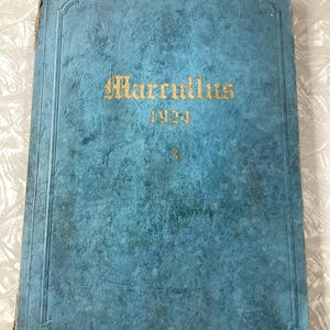 May include: A blue, textured book with gold lettering on the cover. The title is "Marrulius" and the year is "1924".