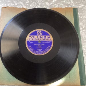 May include: A vintage black vinyl record with a blue and white label. The label reads "COLUMBIA EXCLUSIVE ARTIST" and features the song title "DING-A-RING A RING" by Al Jolson. The record is in its original sleeve.