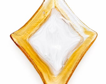 Könnte beinhalten: Eine rautenförmige dekorative Glasschale mit weißem Innenraum und einem gold-bernsteinfarbenen Rand. Die Schale hat ein strukturiertes Aussehen und ist vor einem weißen Hintergrund platziert. Das Design ist modern und elegant.