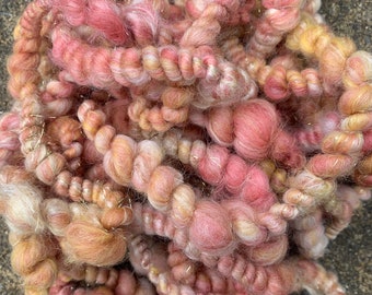 May include: A bundle of pink, white, and yellow yarn with gold glitter. The yarn is soft and fluffy and would be perfect for knitting or crocheting.