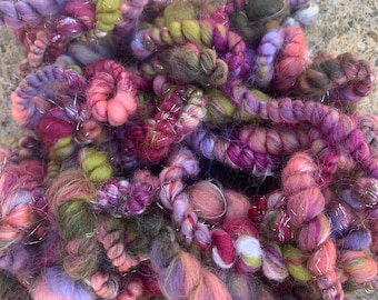 May include: A colorful yarn blend with shades of pink, purple, green, and brown. The yarn has a fluffy texture and includes silver metallic threads.